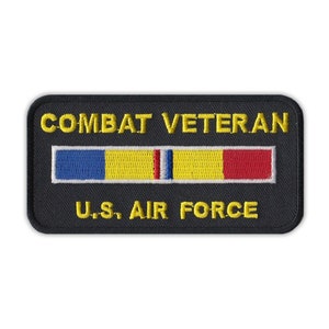 May include: Black embroidered patch with yellow text that reads "Combat Veteran" and "U.S. Air Force". A yellow, blue, red, and white ribbon is centered above the text.