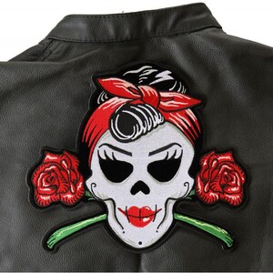 May include: A black leather vest with a red, white, and black embroidered patch of a skull with a red bandana and roses.