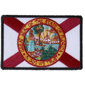 May include: Embroidered patch featuring the state flag of Florida. The patch is white with a red diagonal cross and a circular seal in the center. The seal depicts a sun setting over a body of water with a ship sailing on it. The text "Great Seal of the State of Florida" and "In God We Trust" are inscribed around the seal.