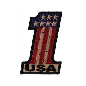 May include: An embroidered patch in the shape of the number one with the American flag design. The patch is red, white, and blue with a black outline and the word "USA" at the bottom.