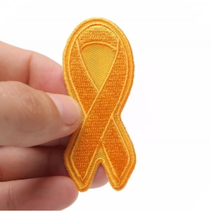 May include: A yellow ribbon embroidered patch. The ribbon is a symbol of support and awareness for various causes.
