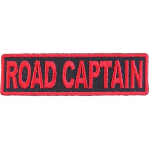 May include: A rectangular patch with the words "ROAD CAPTAIN" embroidered in red on a black background. The border is red. The patch is designed to be sewn or ironed onto clothing or accessories.