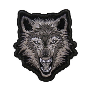 May include: A black and gray embroidered patch of a wolf's head with a snarling expression.
