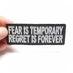 May include: Black patch with white embroidered text that reads "Fear is temporary Regret is forever".