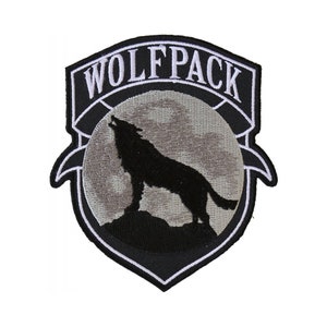 May include: Black and white embroidered patch with a wolf howling at the moon. The patch says "Wolfpack" in white lettering.
