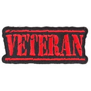 May include: A rectangular black patch with the word "VETERAN" embroidered in red, outlined in red. The patch has a distressed, worn look, with visible thread texture. The patch is designed for apparel.