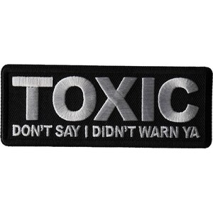 May include: Black embroidered patch with white text that reads "TOXIC DON'T SAY I DIDN'T WARN YA".