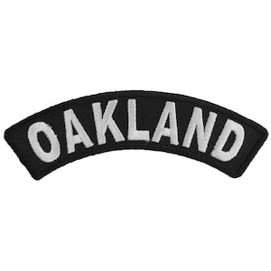 May include: Black and white embroidered patch with the word "OAKLAND" in white lettering.