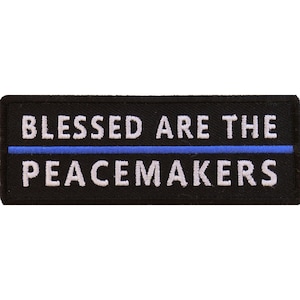 May include: Black embroidered patch with white text that reads "Blessed Are The Peacemakers" with a thin blue line above the text.