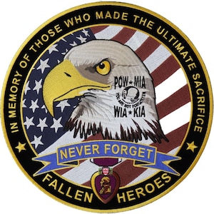 May include: A black and gold circular patch with an American flag in the background. A bald eagle with a yellow beak is in the center of the patch. The eagle is looking to the left. The text "In Memory of Those Who Made the Ultimate Sacrifice" is around the outside of the patch. The text "Never Forget Fallen Heroes" is on a blue ribbon below the eagle. A purple heart medal is below the ribbon. The text "POW*MIA You Are Not Forgotten  WIA*KIA" is on a white circle on the eagle's chest.
