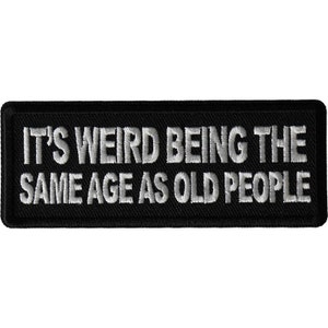 May include: Black embroidered patch with white text that reads "It's weird being the same age as old people."