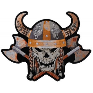 May include: Embroidered patch featuring a skull wearing a Viking helmet with horns and crossed axes. The helmet is decorated with intricate knotwork and has a gold trim. The skull has a fierce expression and braided hair.