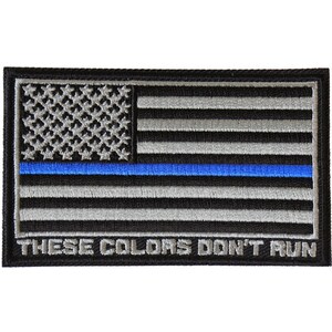 May include: An embroidered patch with a black and white American flag with a blue stripe across the middle. The text "These Colors Don't Run" is below the flag.