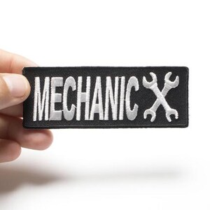 May include: Black embroidered patch with white text that reads "MECHANIC" and two white crossed wrenches.