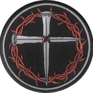 May include: A black and white embroidered patch with a silver cross and a crown of thorns. The cross is made of two nails and the crown of thorns is red.