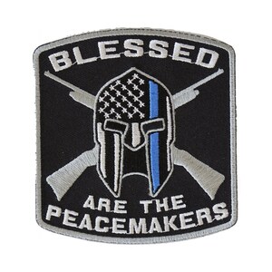 May include: Black and silver embroidered patch with a crossed rifle design, a Spartan helmet with an American flag and a blue line, and the text "Blessed Are The Peacemakers".