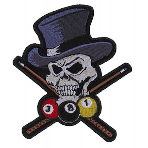 May include: An embroidered patch featuring a skull wearing a top hat and holding crossed pool cues. The skull is white with black eyes and a black mouth. The top hat is blue with a black brim. The pool cues are brown with white tips. There are three billiard balls in the center of the patch: a red ball with the number 3, a black ball with the number 8, and a yellow ball with the number 1.