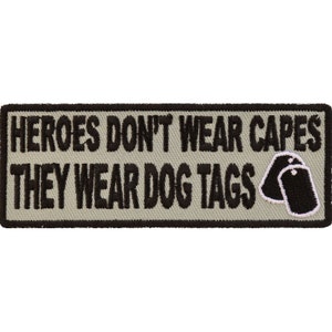 May include: A gray embroidered patch with black text that reads "Heroes don't wear capes they wear dog tags". The patch features two black dog tags with white outlines.