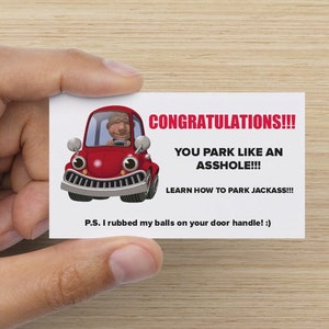 May include: A white card with the text "CONGRATULATIONS!!! YOU PARK LIKE AN ASSHOLE!!! LEARN HOW TO PARK JACKASS!!! P.S. I rubbed my balls on your door handle! :)" and a cartoon red car.