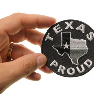 May include: A black and white embroidered patch with the text "Texas Proud" and an outline of the state of Texas with a white star.