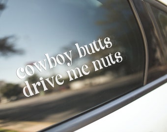 May include: A white vinyl sticker on a car window that reads "cowboy butts drive me nuts".