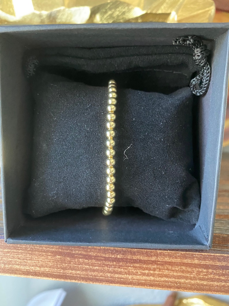 May include: A gold beaded bracelet in a black velvet box.