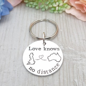 May include: Silver keyring with a round tag that reads "Love knows no distance". The tag features an outline of the United Kingdom and Australia with a dotted line connecting them and a heart symbol.