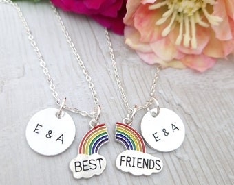 Puede incluir: Dos collares de plata con dijes de arcoíris y discos personalizados que dicen "E & A" y "Mejores amigos".