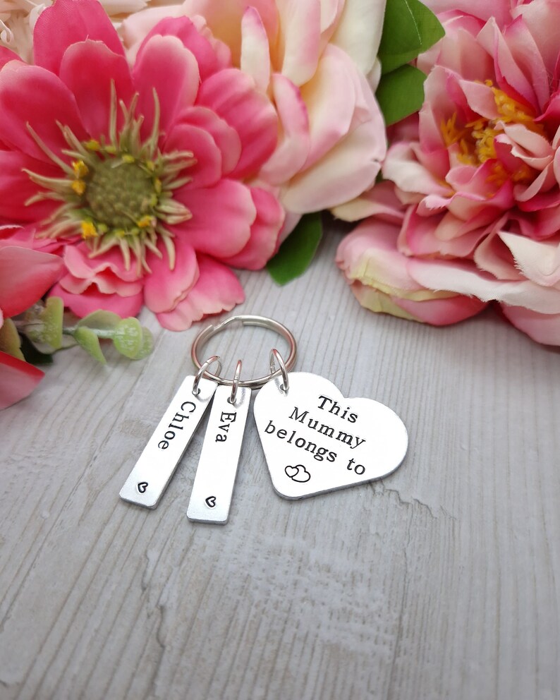 May include: Silver keyring with three tags. The tags are engraved with the names "Chloe", "Eva", and "This Mummy belongs to". The keyring has a heart-shaped charm with two small hearts engraved on it.