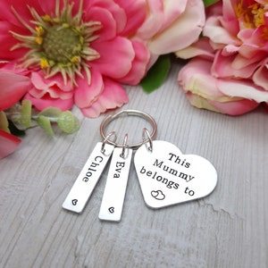 May include: Silver keyring with a heart-shaped charm that says "This Mummy belongs to" with two small hearts above the word "to".  The keyring also has two rectangular charms with the names "Chloe" and "Eva" engraved on them.