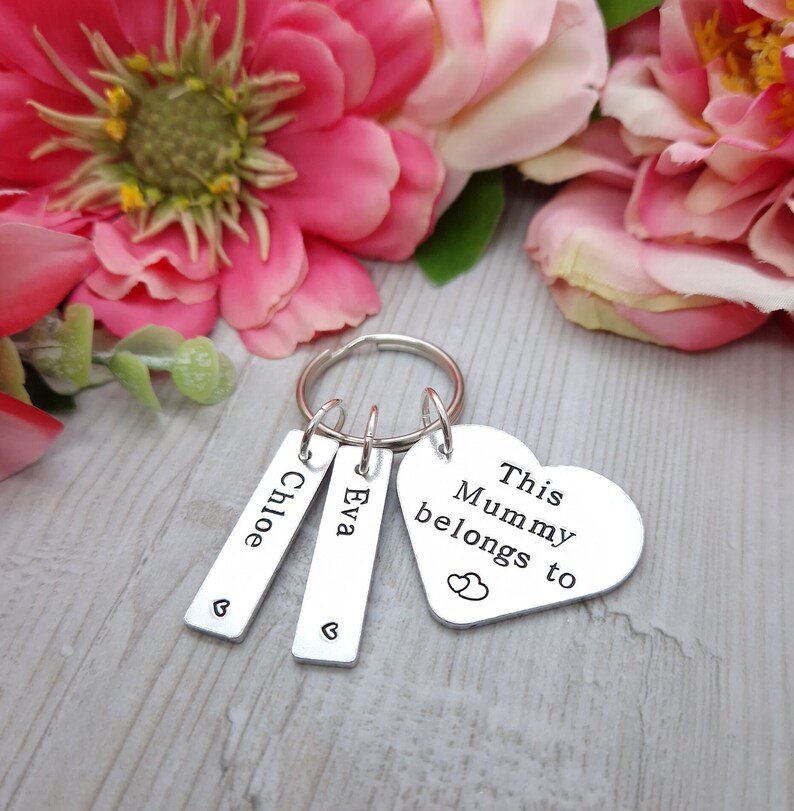 May include: Silver keyring with a heart-shaped charm that says "This Mummy belongs to" with two small hearts above the word "to".  The keyring also has two rectangular charms with the names "Chloe" and "Eva" engraved on them.