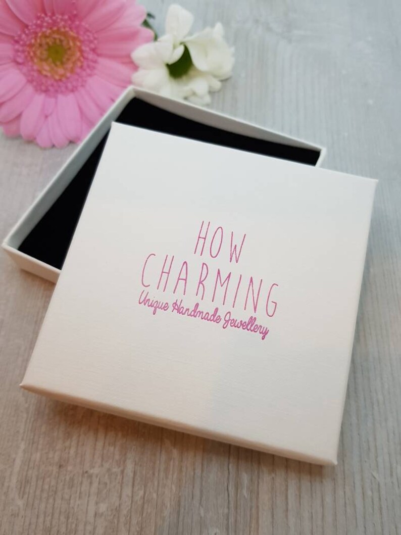 May include: White gift box with a pink lid. The lid has the text "HOW CHARMING Unique Handmade Jewellery" printed on it.