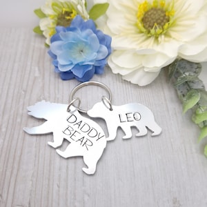 May include: Silver bear keychain with the text "Daddy Bear" on one bear and "Leo" on the other bear.