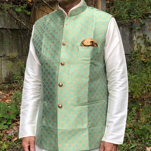 Peut inclure: Un gilet brod&eacute; de couleur vert menthe et or avec un col mandarin et une fermeture &agrave; boutons. Le gilet a une poche sur le c&ocirc;t&eacute; gauche avec un bouton dor&eacute; et un mouchoir de poche marron.