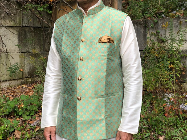 Peut inclure: Un gilet brod&eacute; de couleur vert menthe et or avec un col mandarin et une fermeture &agrave; boutons. Le gilet a une poche sur le c&ocirc;t&eacute; gauche avec un bouton dor&eacute; et un mouchoir de poche marron.