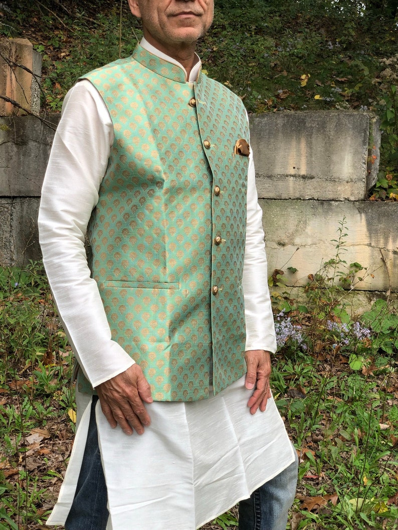 Peut inclure: Un gilet vert menthe avec un motif dor&eacute; et des boutons dor&eacute;s. Le gilet est port&eacute; sur une chemise blanche &agrave; manches longues.