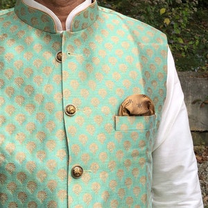 Peut inclure: Un gilet vert menthe avec un motif floral dor&eacute; et des boutons dor&eacute;s. Un mouchoir de poche marron est dans la poche.