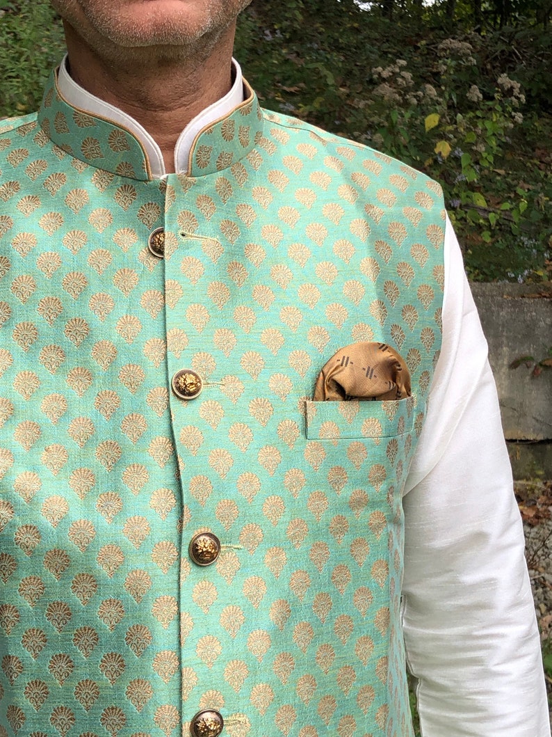 Peut inclure: Un gilet vert menthe avec un motif floral dor&eacute; et des boutons dor&eacute;s. Un mouchoir de poche marron est dans la poche.