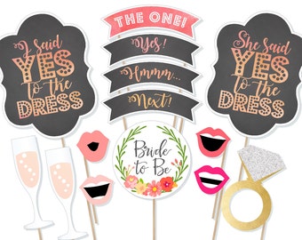 May include: A set of 10 photo booth props for a bridal shower or wedding. The props include a bride to be sign, a ring, lips, champagne glasses, and signs that say "I said yes to the dress" and "She said yes to the dress".