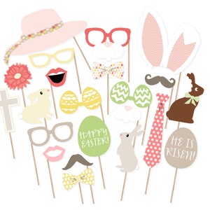 May include: A set of 16 Easter-themed photo booth props. The props include a pink hat, bunny ears, glasses, lips, mustaches, bow ties, eggs, a cross, a bunny, and signs that say "Happy Easter!" and "He is Risen!"