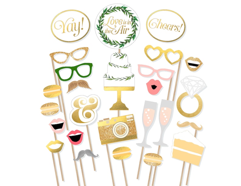 May include: A set of 20 gold and white wedding photo booth props. The props include a cake, champagne flutes, a ring, a camera, a mustache, lips, glasses, and more. The props are on sticks and are ready to be used for wedding photos.