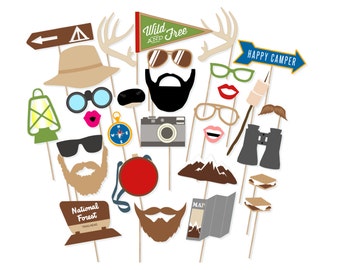 May include: A set of 16 colorful camping-themed photo booth props. The props include a lantern, a compass, a camera, a pair of binoculars, a mountain, a map, a s'more, a mustache, a pair of lips, a pair of glasses, a hat, a pair of antlers, a sign that says "Wild and Free", a sign that says "Happy Camper", and a sign that says "National Forest Trailhead".