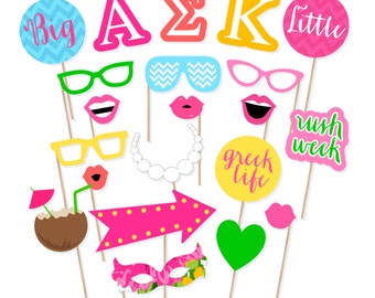 May include: A set of 14 colorful photo booth props with a Greek sorority theme. The props include letters, glasses, lips, a coconut drink, a heart, an arrow, a mask, a necklace, and signs that say "Big", "Little", "Greek Life", and "Rush Week".