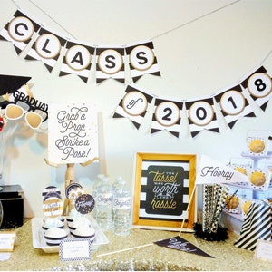 May include: Black and gold graduation party decorations with a banner that says "Class of 2018", cupcakes, and a sign that says "The tassel was worth the hassle".