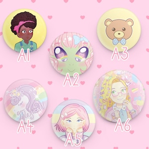 Puede incluir: Seis botones redondos coloridos con diferentes ilustraciones. Los botones muestran a una niña con piel morena y una diadema, un extraterrestre verde con cabello rosado, un oso marrón con una corbata de lazo azul, un unicornio con un fondo de arcoíris, una niña con cabello rosado y un fondo de arcoíris, y una niña con cabello rubio y un fondo de arcoíris.