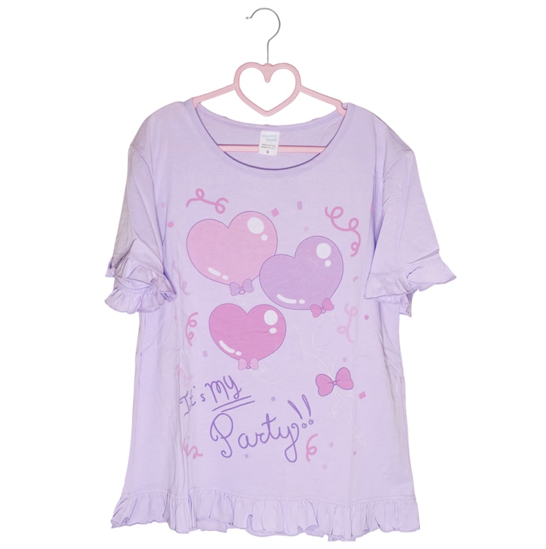 May include: A lavender t-shirt with a ruffled hem and short sleeves. The shirt features a graphic of three pink and purple heart-shaped balloons with bows and the text "It's my Party!" in pink.
