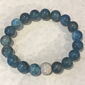 May include: A blue agate beaded bracelet with a silver and white sparkly bead in the center.