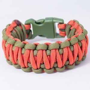 May include: A green and orange paracord bracelet with a black plastic buckle.
