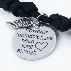 Puede incluir: Pulsera de paracord negro con un dije de plata que dice "Forever wouldn't have been long enough." El dije tiene un pequeño ala de ángel.