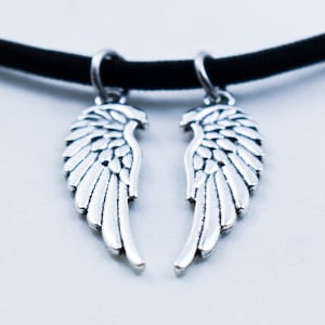 May include: A black choker necklace with two silver angel wing charms.
